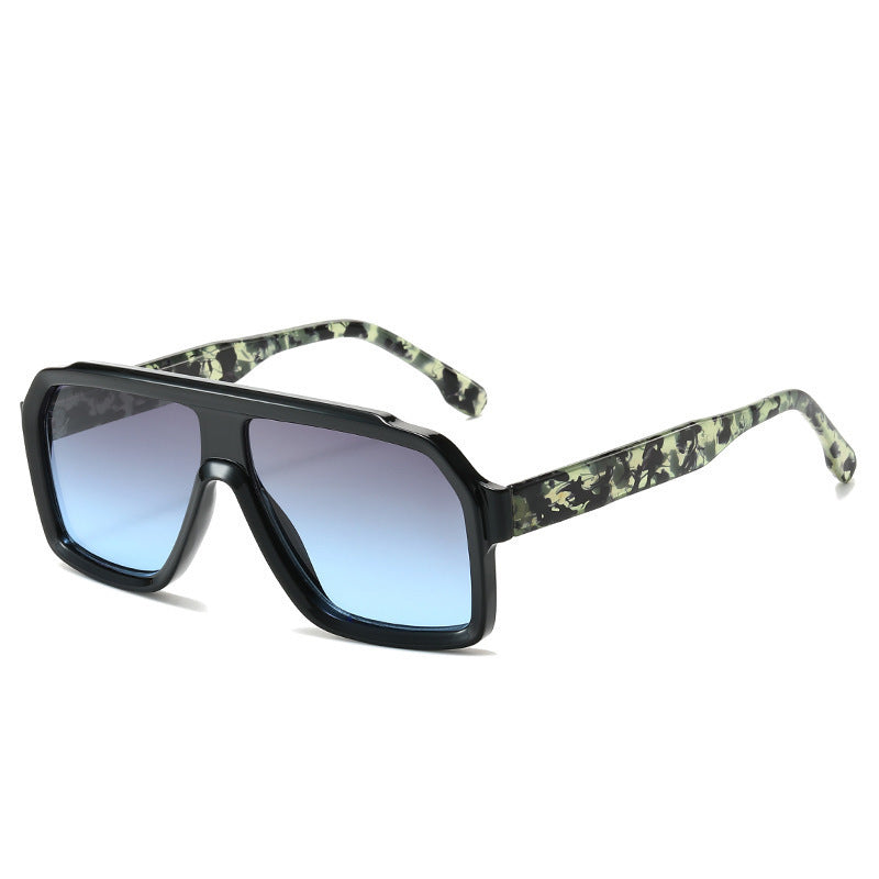 Sunglasses with green camouflage frame and blue gradient lenses on a white background