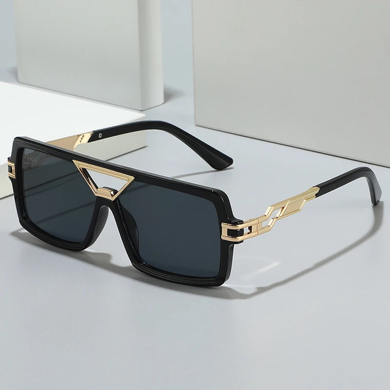 Sunglasses with black frames and gold accents on a light gray background