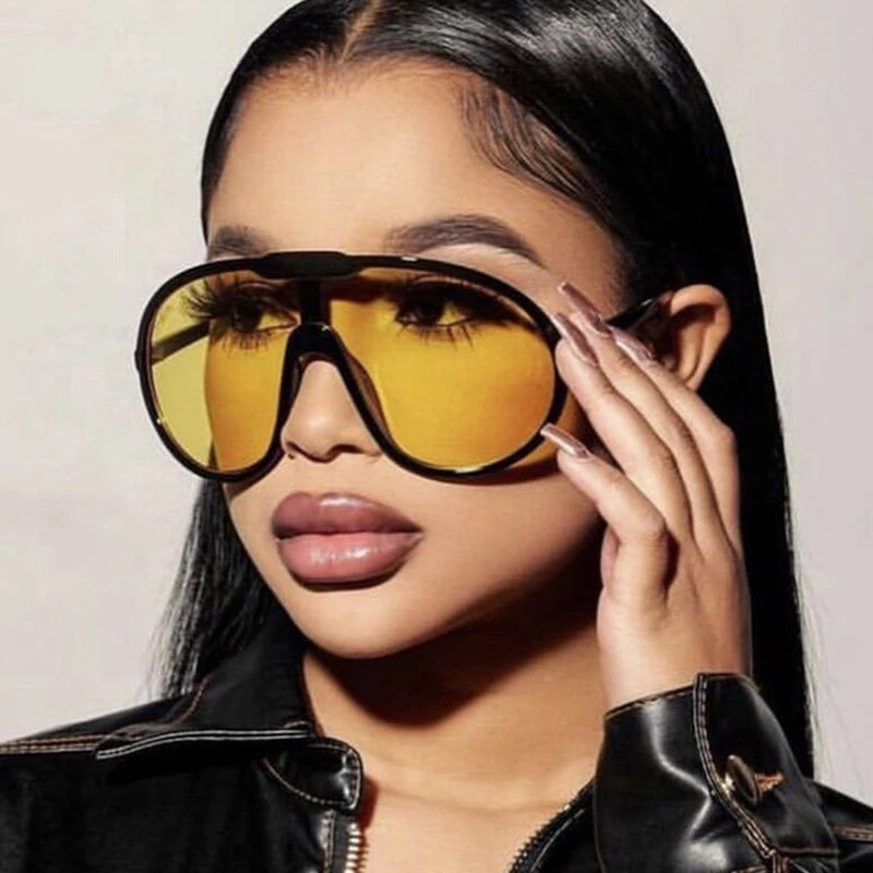 Woman wearing large yellow sunglasses and a black leather jacket.