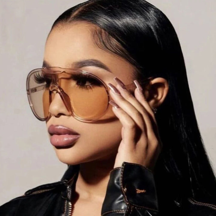 Woman wearing large sunglasses with a neutral background